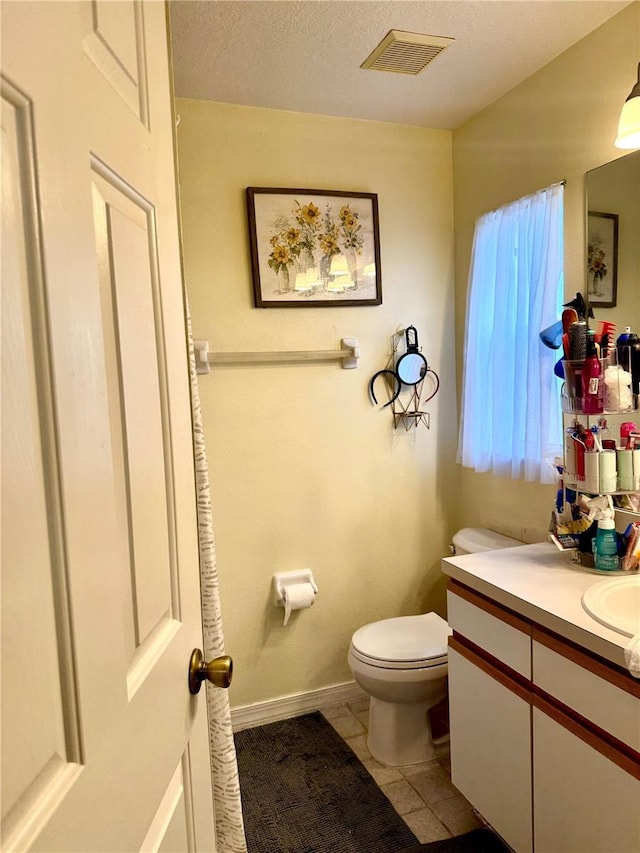 half bathroom featuring vanity, toilet, tile patterned floors, a textured ceiling, and visible vents