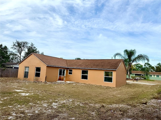 back of property featuring stucco siding and fence