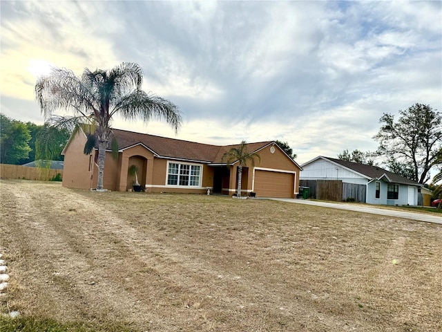 ranch-style home with an attached garage, stucco siding, fence, and driveway