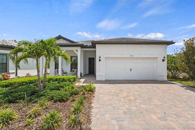 ranch-style house with a tiled roof, decorative driveway, stucco siding, and a garage