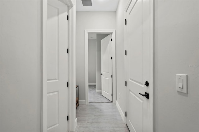 hallway featuring baseboards and visible vents