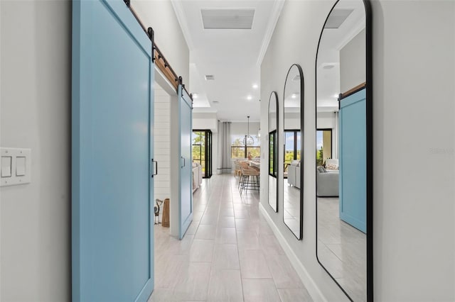 hallway featuring light tile patterned floors, visible vents, a barn door, and ornamental molding