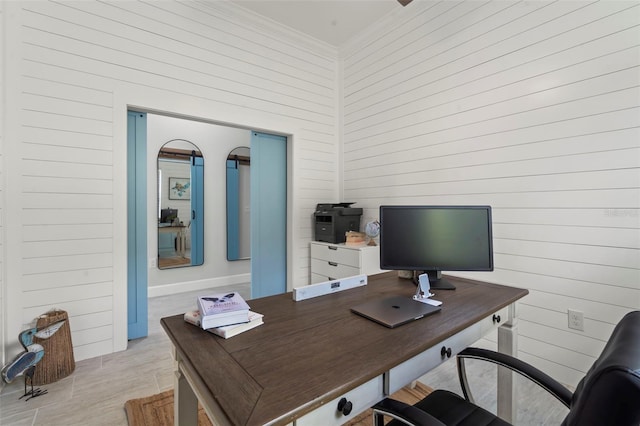 office space with crown molding, wood walls, and light wood-type flooring