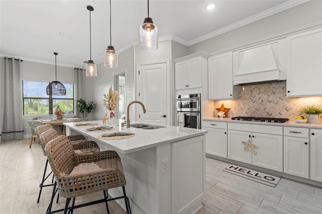 kitchen featuring stainless steel double oven, gas stovetop, a sink, custom range hood, and white cabinetry