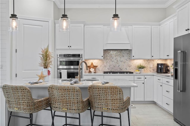 kitchen featuring crown molding, tasteful backsplash, a sink, white cabinets, and stainless steel appliances
