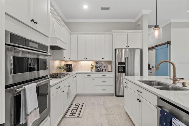 kitchen featuring visible vents, appliances with stainless steel finishes, a barn door, a sink, and white cabinets
