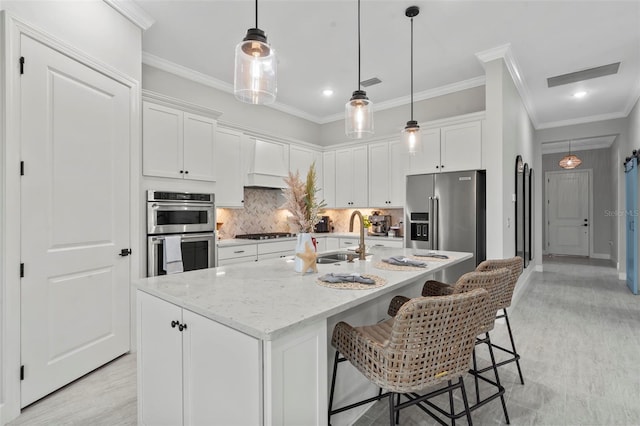 kitchen with crown molding, appliances with stainless steel finishes, a sink, white cabinetry, and tasteful backsplash