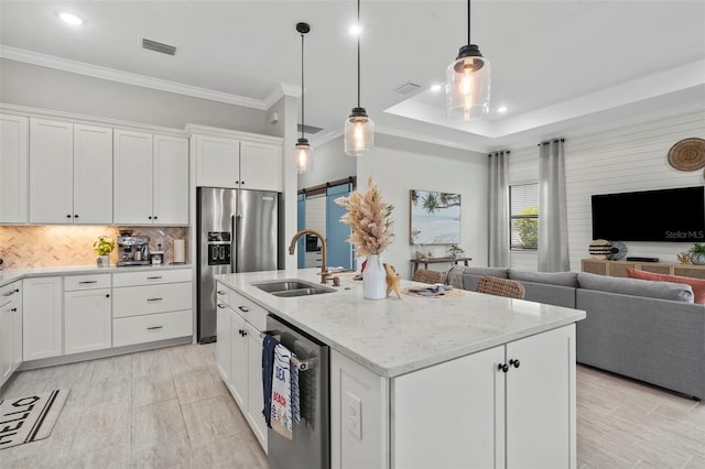 kitchen with appliances with stainless steel finishes, a sink, open floor plan, backsplash, and visible vents