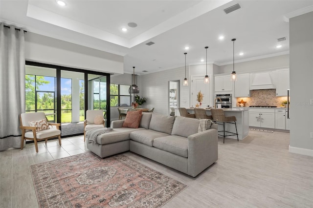 living area featuring visible vents, recessed lighting, and ornamental molding