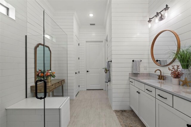 full bath with vanity, crown molding, visible vents, wood finished floors, and a stall shower