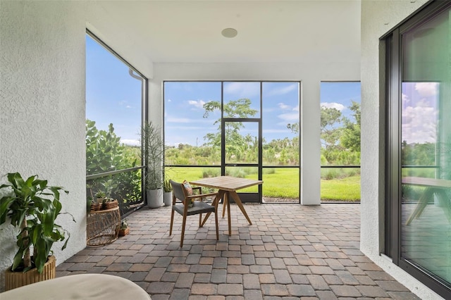 sunroom featuring a textured wall and brick floor