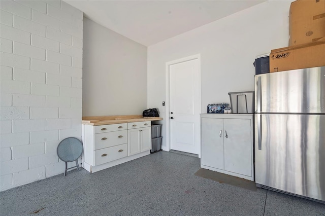 kitchen with freestanding refrigerator, white cabinetry, dark speckled floor, and light countertops