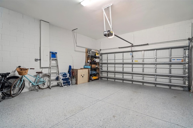garage featuring concrete block wall and a garage door opener