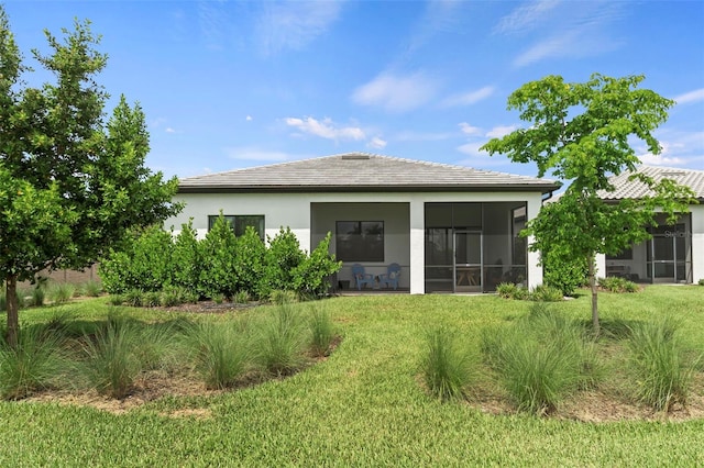 back of house with a lawn, stucco siding, a sunroom, and a tile roof
