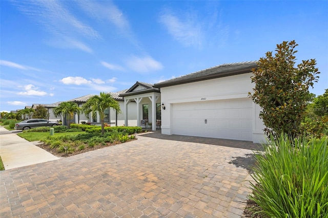 view of front of property featuring a garage, decorative driveway, stucco siding, and a tile roof