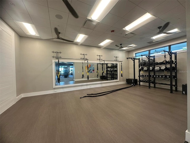 workout area featuring baseboards, a drop ceiling, and wood finished floors