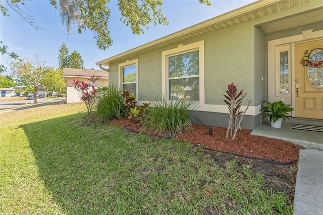 view of home's exterior with stucco siding and a lawn