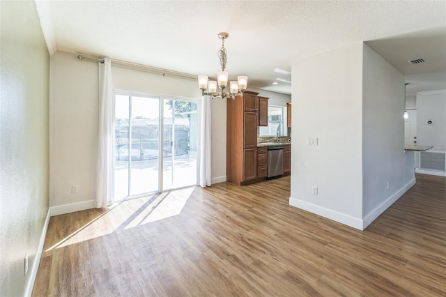 unfurnished dining area featuring a chandelier, wood finished floors, baseboards, and a sink