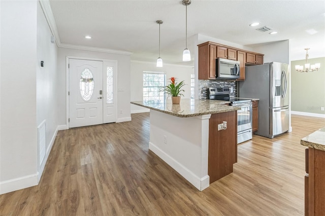 kitchen featuring stainless steel appliances, brown cabinetry, ornamental molding, baseboards, and light wood-style flooring