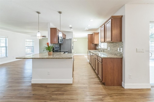 kitchen featuring stainless steel appliances, a sink, baseboards, decorative backsplash, and crown molding