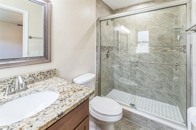 bathroom with toilet, a shower stall, and vanity