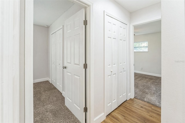 hallway featuring carpet flooring and baseboards