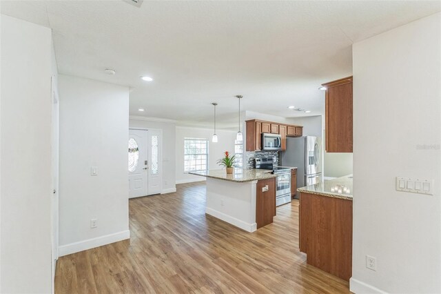 kitchen featuring appliances with stainless steel finishes, light wood finished floors, brown cabinetry, baseboards, and recessed lighting