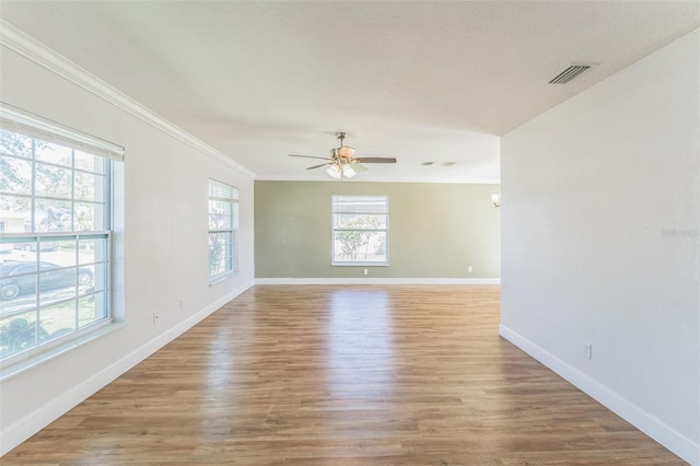 empty room with ornamental molding, ceiling fan, light wood-type flooring, and baseboards