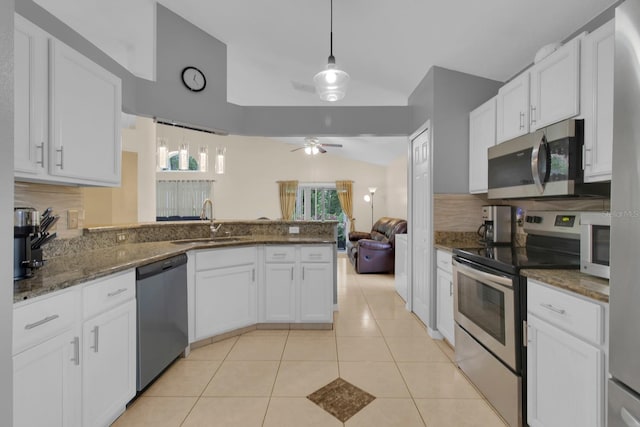2398 Queenswood Cir, Kissimmee, FL 34743 - kitchen with appliances with stainless steel finishes, a peninsula, backsplash, vaulted ceiling, and white cabinets