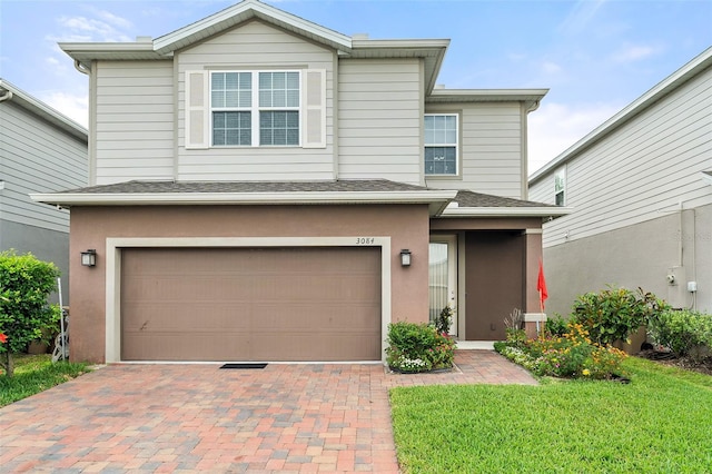 3084 Slough Creek Dr, Kissimmee, FL 34744 - traditional-style home featuring a garage, decorative driveway, a front lawn, stucco siding, and roof with shingles