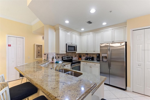 kitchen with stainless steel appliances, a sink, a peninsula, light tile patterned floors, and crown molding