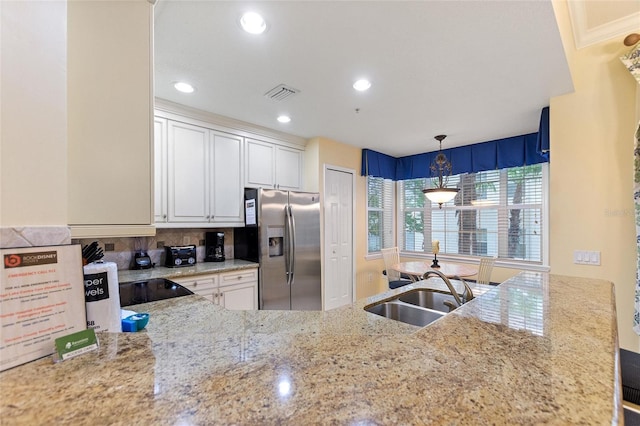 kitchen featuring stainless steel refrigerator with ice dispenser, a sink, backsplash, light stone counters, and white cabinetry