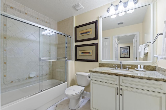 bathroom with toilet, tile patterned flooring, vanity, and bath / shower combo with glass door