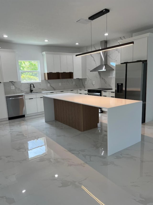 kitchen featuring wall chimney range hood, modern cabinets, stainless steel appliances, a center island, and recessed lighting