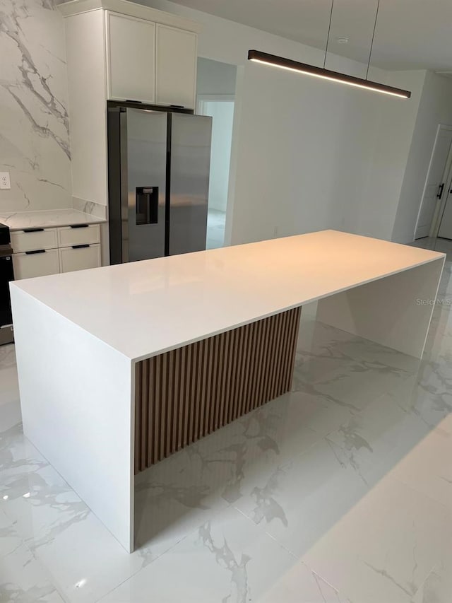 kitchen with stainless steel fridge with ice dispenser, light marble finish floors, white cabinets, and light countertops