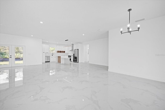 unfurnished living room featuring a chandelier, light marble finish flooring, french doors, and recessed lighting