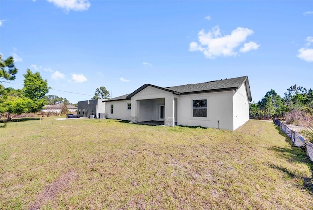 rear view of property featuring stucco siding and a lawn
