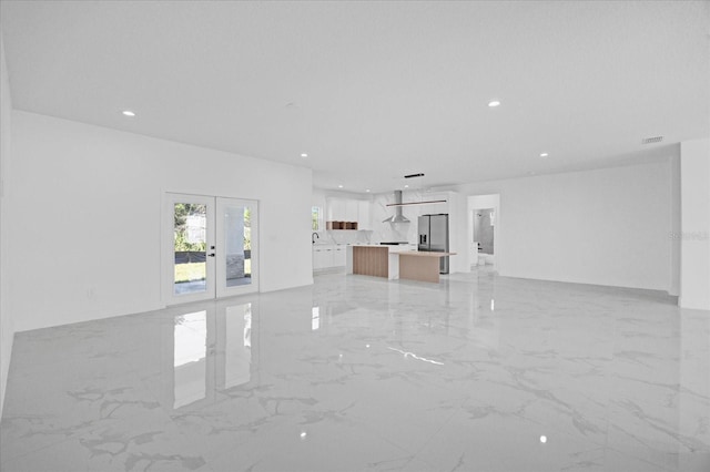 unfurnished living room featuring french doors, light marble finish flooring, and recessed lighting