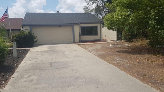 single story home featuring an attached garage, a shingled roof, stucco siding, and concrete driveway