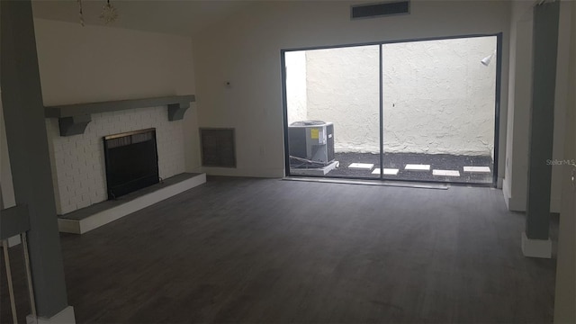 unfurnished living room featuring visible vents, a brick fireplace, and wood finished floors