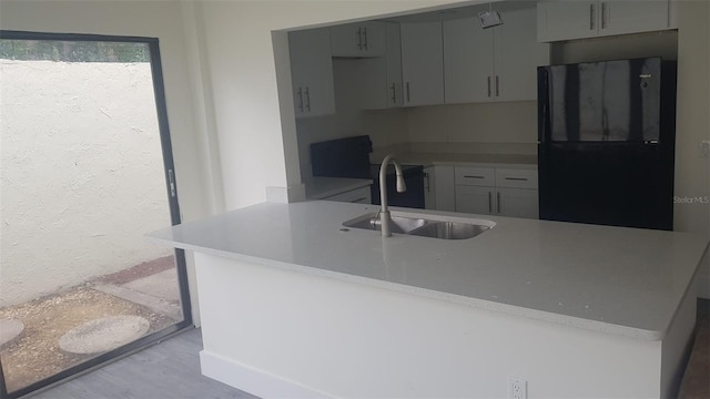 kitchen with a sink, light wood-style floors, light countertops, freestanding refrigerator, and gray cabinetry