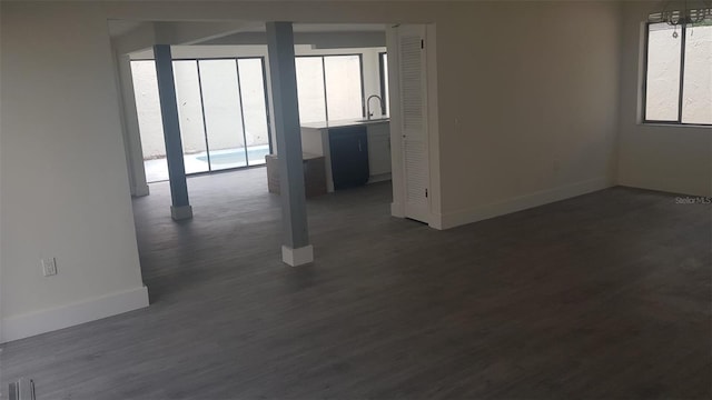 spare room featuring baseboards, a sink, and dark wood-style flooring