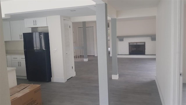 interior space with baseboards, freestanding refrigerator, wood finished floors, and white cabinetry