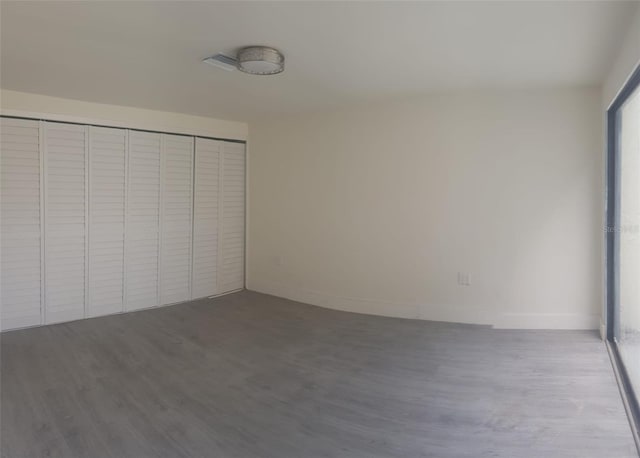 unfurnished bedroom with a closet, baseboards, and wood finished floors