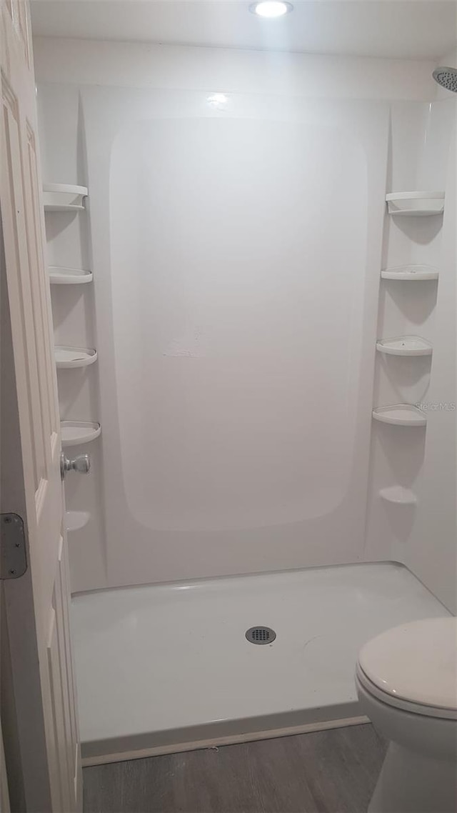 full bath with walk in shower, wood finished floors, and toilet