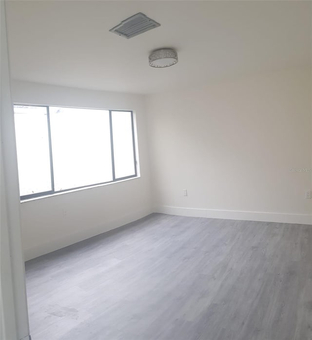 empty room with visible vents, baseboards, and wood finished floors
