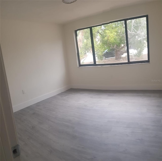 unfurnished room with baseboards and wood finished floors