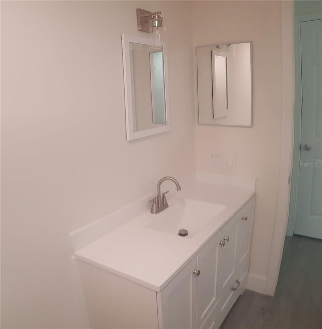 bathroom featuring vanity, baseboards, and wood finished floors