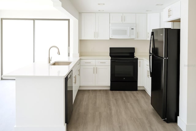 7314 Patio Row, Hudson, FL 34667 - kitchen with black appliances, light wood-type flooring, white cabinets, and light countertops