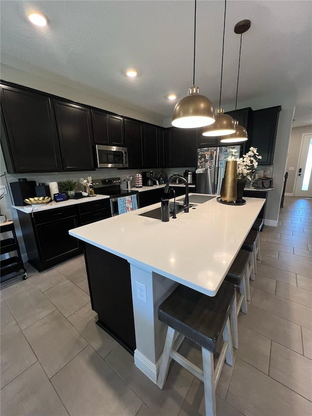 kitchen with dark cabinetry, light countertops, a kitchen bar, and stainless steel appliances